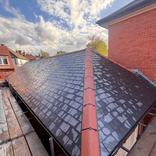 Slate-effect re-roof with terracotta dry ridge, scaffold alongside