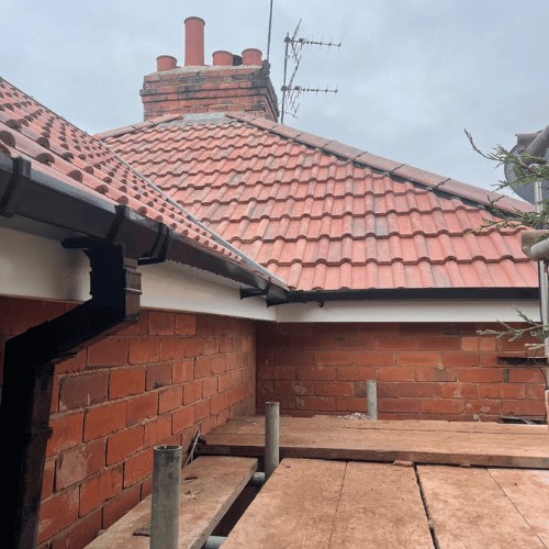 Red tiled hip roof with new white guttering