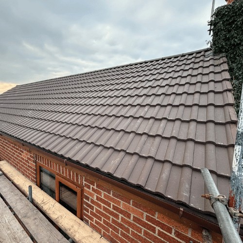 Brown interlocking tiles on a finished roof over red brick